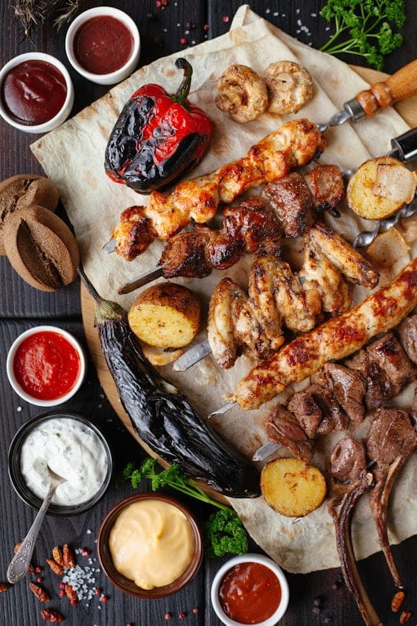 Platter of grilled chicken skewers, wings and roasted vegetables